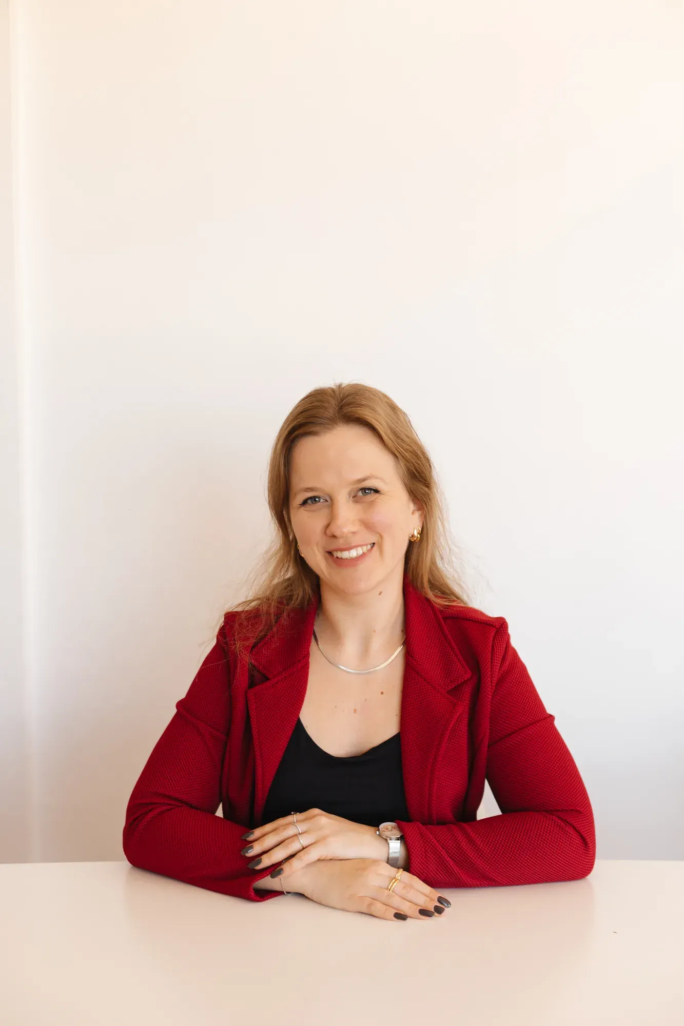 Mari, professora de alemão, sentada à mesa e sorrindo para a câmera